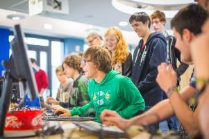 A group of students smiling and looking at a PC monitor